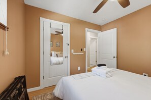 Ein Schlafzimmer mit einem Bett, einem Deckenventilator und einer Tür zu einem anderen Raum.
