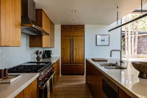 A modern kitchen with wooden cabinets, a stainless steel refrigerator, and a large window. - Site Line Ski-In/Ski-Out at Northstar by Tahoe Getaways - Pet-Friendly 4BR w Hot Tub & HOA (Truckee)