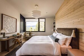 A bedroom with a bed, a desk, and a chair. There is a window with a view of mountains. - Site Line Ski-In/Ski-Out at Northstar by Tahoe Getaways - Pet-Friendly 4BR w Hot Tub & HOA (Truckee)