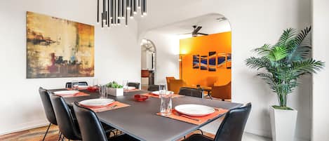 Un espace de salle à manger moderne, avec une longue table, des chaises noires et un luminaire contemporain.