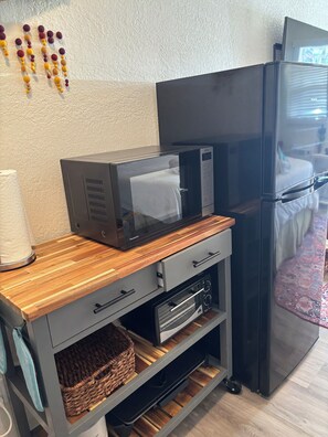 A compact kitchenette with a microwave, a refrigerator, and a wooden countertop. - Delightful beach condo with cool breezes and beach vibes (Venice)