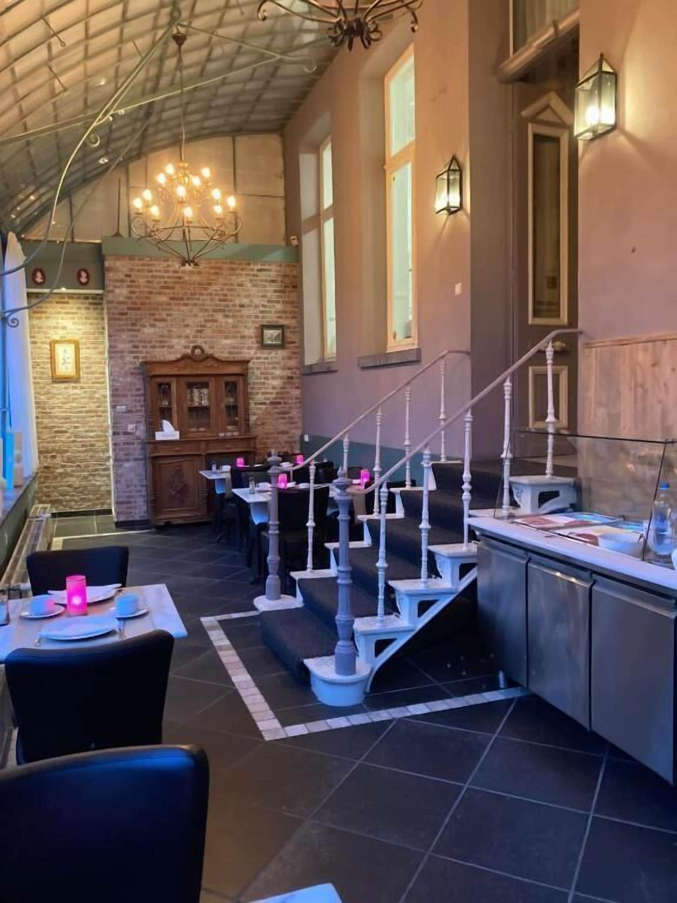 Un restaurant avec un mur en briques, un escalier et un lustre.