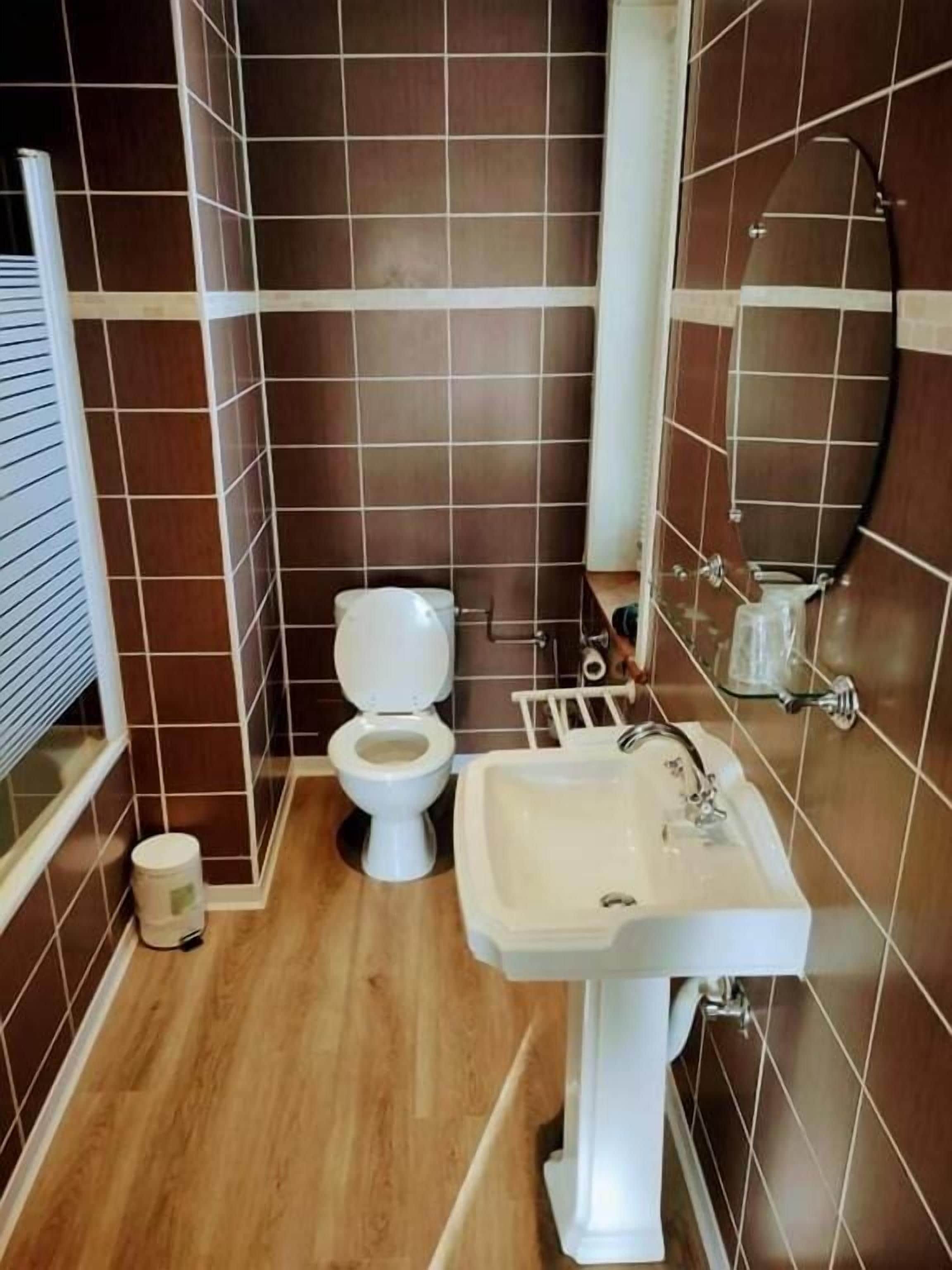 A bathroom with a toilet, sink, and mirror.