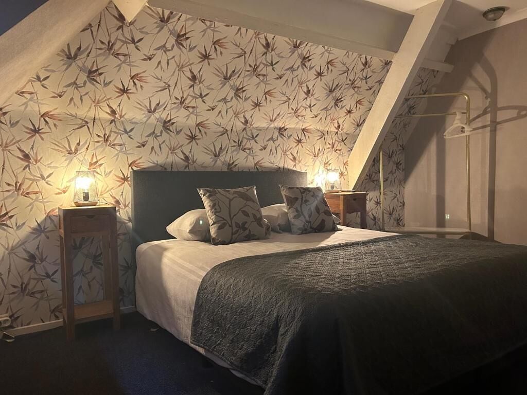 A bedroom with a bed, two bedside tables, and a wall with a leaf pattern.