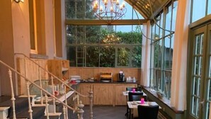 An indoor dining area with tables, chairs, and a staircase. - Hotel Vredehof (Damme)