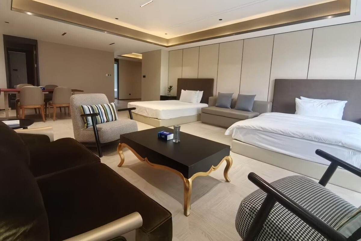 Ett modernt hotellrum med en stor säng, en soffa, ett matbord och en separat sittgrupp.