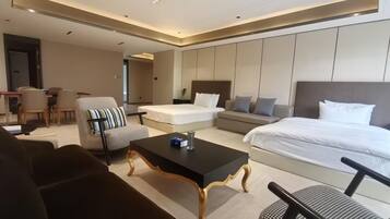 Una habitación de hotel moderna con una cama grande, un sofá, una mesa de comedor y una zona de estar separada.