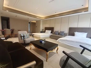 Ett modernt hotellrum med en stor säng, en soffa, ett matbord och en separat sittgrupp.