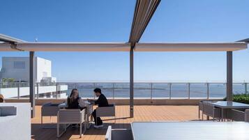Una terraza al aire libre con asientos y vistas al mar.