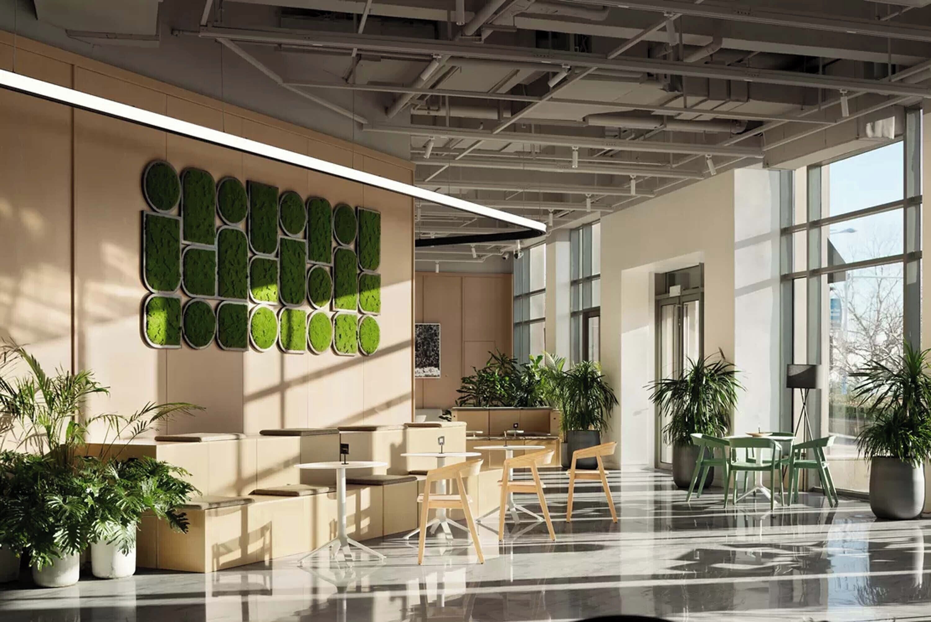 Interior de oficina moderno con un amplio panel de plantas verdes en la pared, varias macetas y un diseño espacioso con mesas y sillas.
