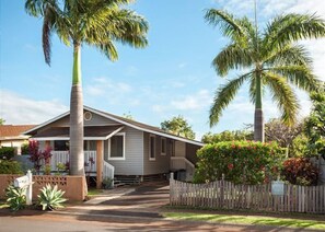 A single-story house with a front porch, a picket fence, and a palm tree in the yard. - MAUI PAIA HOUSE Walk to beach and charming Paia town! (Paia)