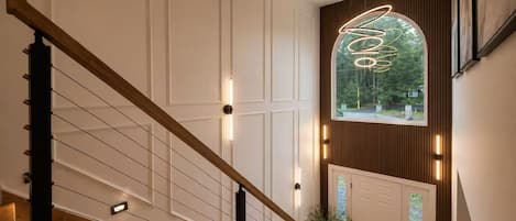A staircase with a wooden handrail and wall-mounted lights, leading to a door with a frosted glass panel.
