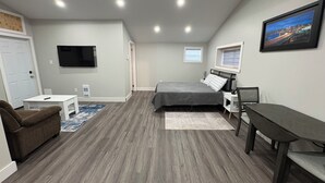 Une chambre à coucher avec un lit, un bureau, une chaise, une télévision et une fenêtre.
