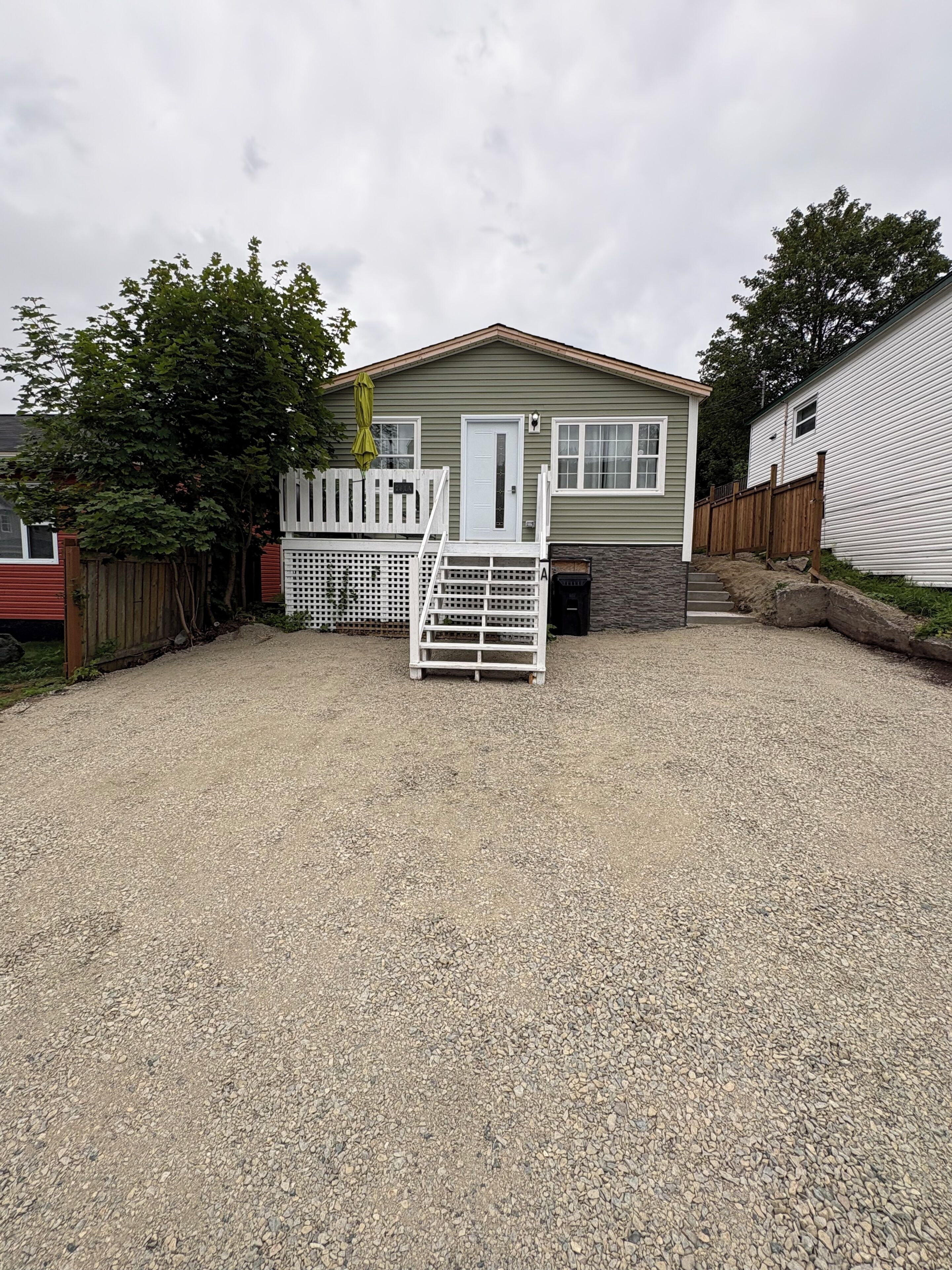 A single-story house with a gravel driveway and a white fence.