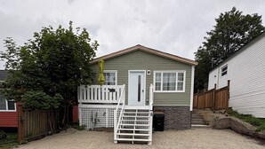 Une maison de plain-pied avec une allée en gravier et une clôture blanche.