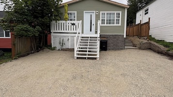 A single-story house with a gravel driveway and a white fence.