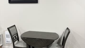 A dining area with a table and chairs, a framed picture on the wall, and a white radiator.