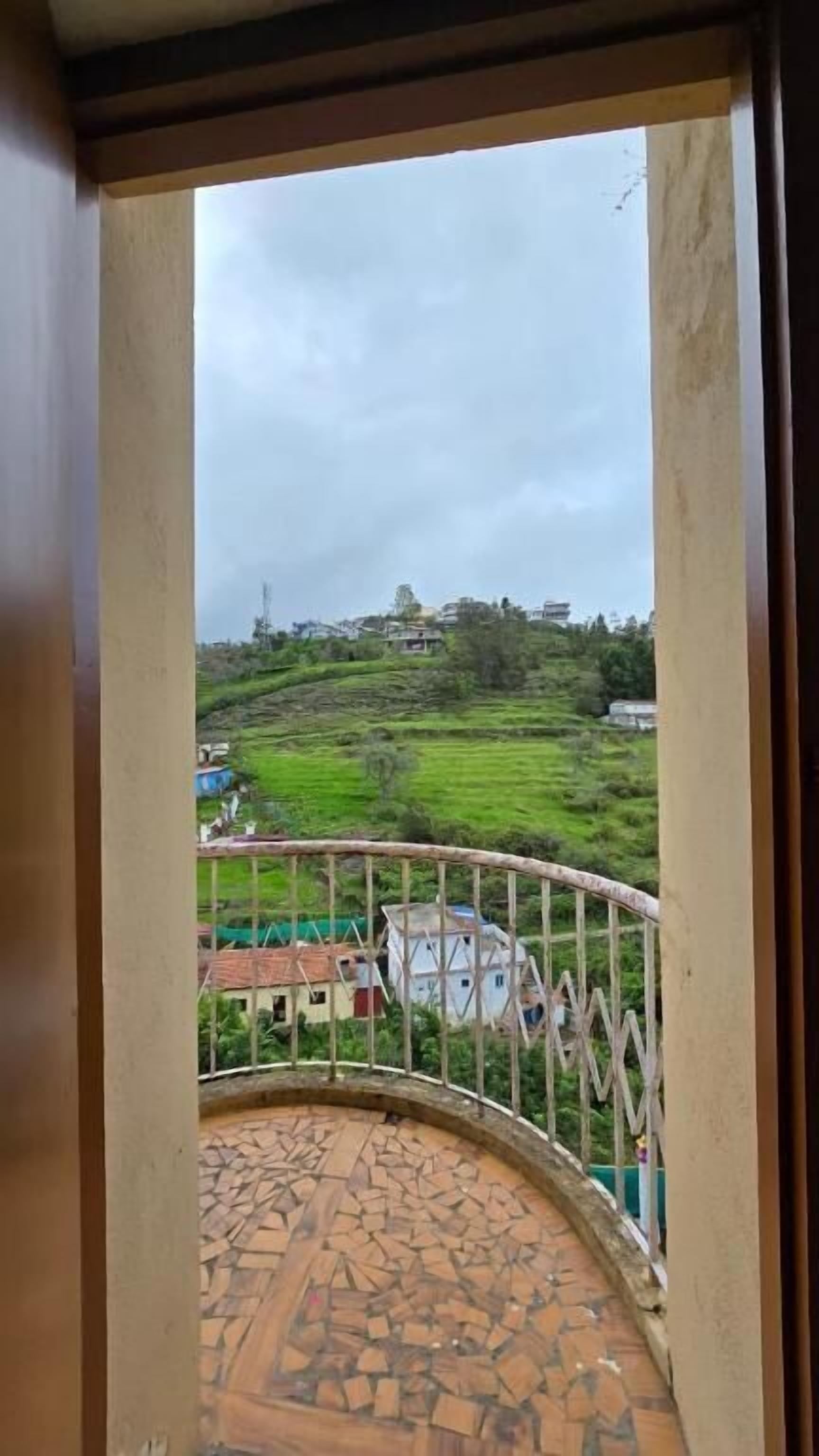 Uma varanda com vista para uma paisagem verde e edifícios.