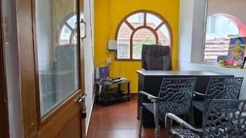 Quarto com porta de madeira, parede amarela e janela com vista.
