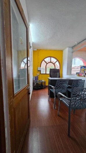 A room with a wooden door, a yellow wall, and a window with a view. - Vedha Holidays (Kodaikanal)
