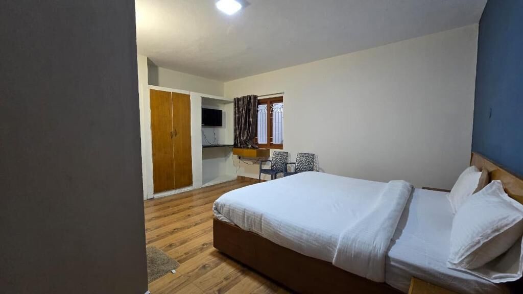 A bedroom with a bed, a wardrobe, a desk, and a chair.