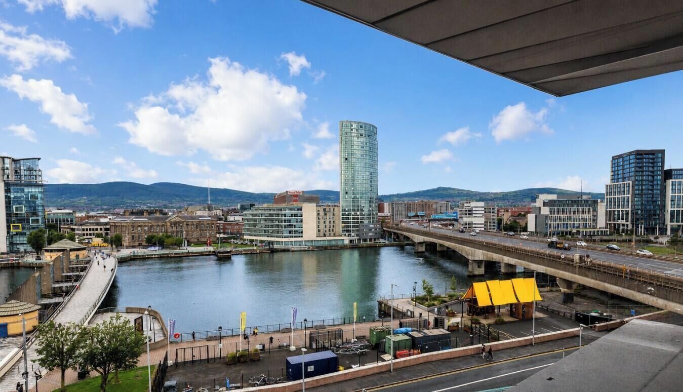 A cityscape with a river, modern buildings, and a bridge.