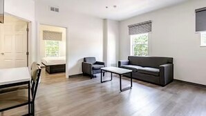 A modern living room with a sofa, a coffee table, and a dining area with chairs.