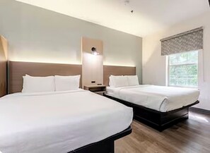 A hotel room with two beds, a nightstand, and a window with a view. - Newly Renovated Hotel - 2 Bedroom Suites with Kitchen in adorable Columbia (Columbia)