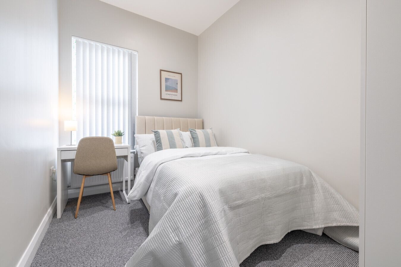 Un dormitorio con cama, escritorio y silla.