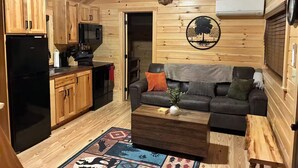 A cabin interior with a kitchen, a living area, and a mounted deer head.