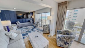 A modern hotel room with a sofa, armchairs, a coffee table, and a large window offering a view of the sea. - Spacious Islander Beach Resort 506 - sleeps 10 with washer dryer (Fort Walton Beach)