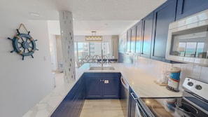 A modern kitchen with dark cabinets, a white countertop, and a built-in oven. - Spacious Islander Beach Resort 506 - sleeps 10 with washer dryer (Fort Walton Beach)