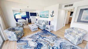 A living room with a sofa, coffee table, and patterned armchairs. There is a painting of a sailboat on the wall. - Spacious Islander Beach Resort 506 - sleeps 10 with washer dryer (Fort Walton Beach)