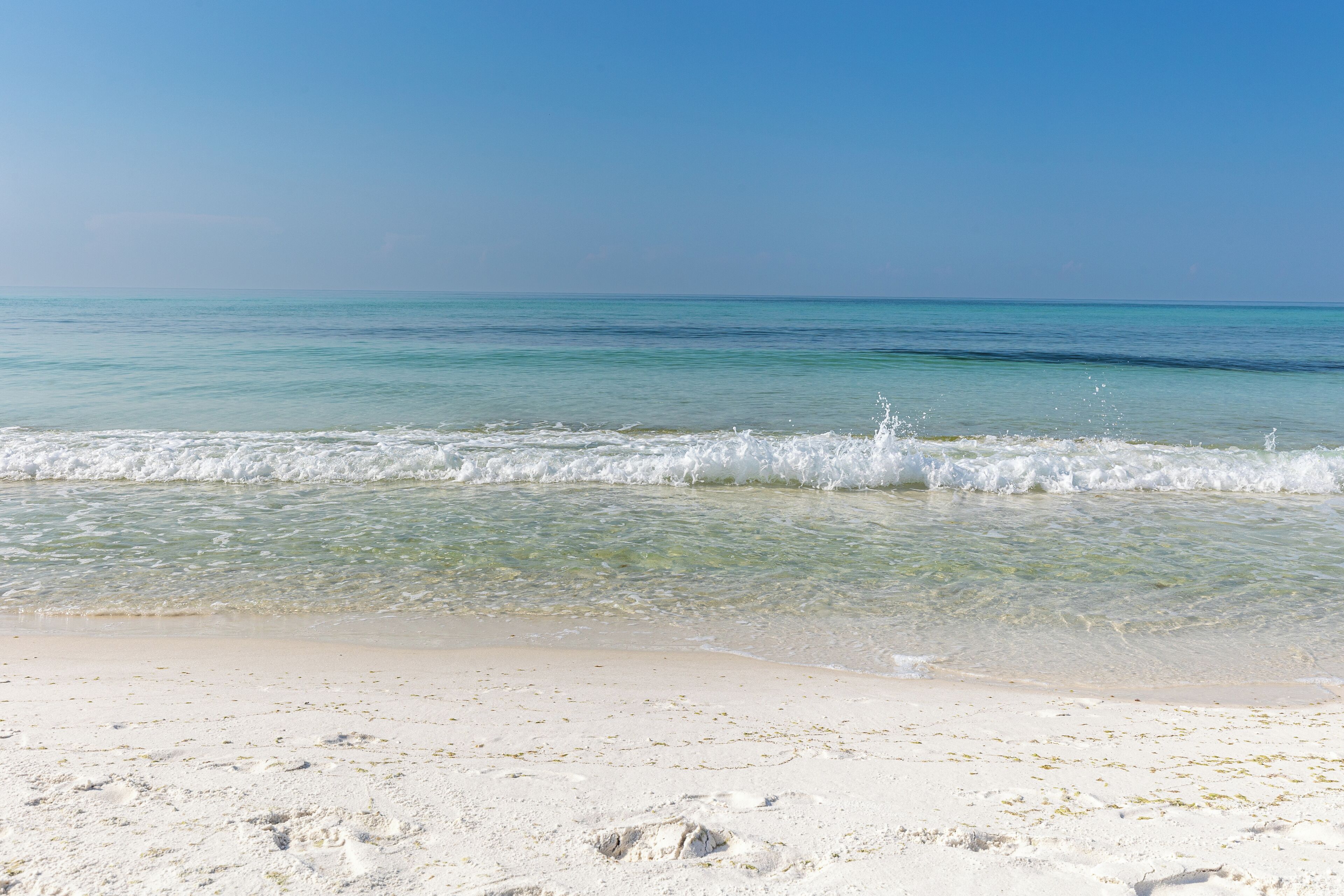 Una playa con aguas turquesas cristalinas, arena blanca y olas suaves.