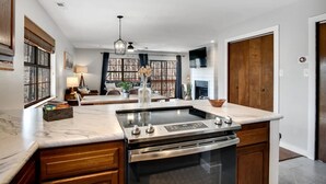 Una cocina moderna con estufa integrada, armarios de madera y encimera de mármol.