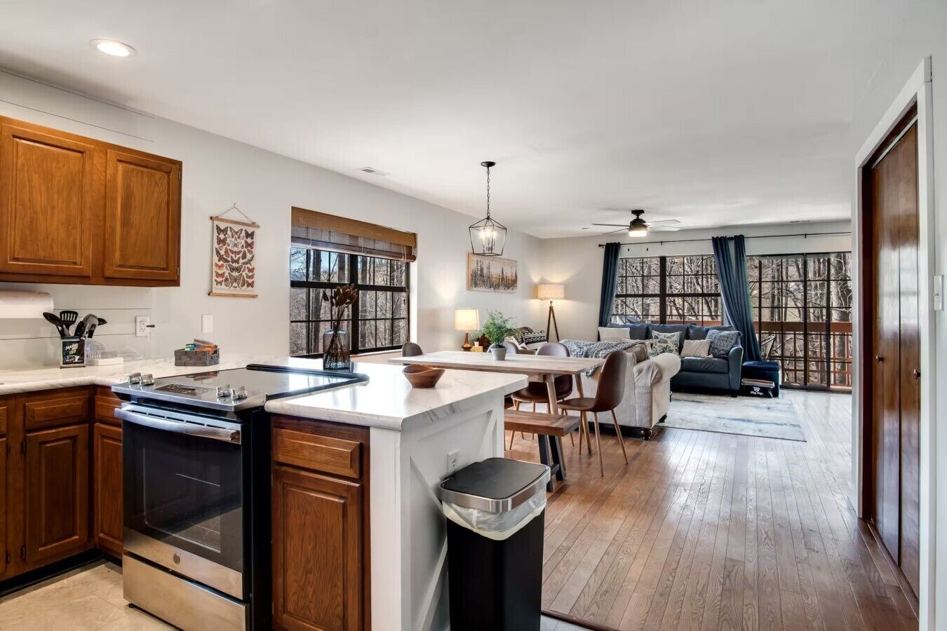 A modern kitchen with wooden cabinets, a large island, and a dining area with a sofa.