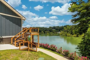 A wooden staircase leading to a building with a view of a lake and surrounding greenery. - ⚓ Private Dock Cabin | Pet-Friendly, Hot Tub, Game Room, Arcade, Sleeps 12 Guest (Sevierville)