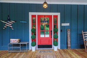 A red door with a welcome mat, a star decoration, and a welcome sign. - ⚓ Private Dock Cabin | Pet-Friendly, Hot Tub, Game Room, Arcade, Sleeps 12 Guest (Sevierville)