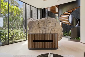 A modern interior with a large rock centerpiece, a wooden slatted structure, and a curved staircase. - Exclusive 6BR Ocean-View Villa with detached apartment - Peninsula Papagayo (Peninsula Papagayo, Nacascolo)