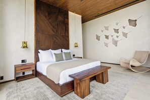 A modern bedroom with a wooden headboard, a large bed with white bedding, a bench, a chair, and wall art. - Exclusive 6BR Ocean-View Villa with detached apartment - Peninsula Papagayo (Peninsula Papagayo, Nacascolo)