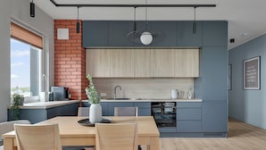 Una cocina moderna con una pared de ladrillo decorativa, armarios de madera y una zona de comedor con mesa y sillas.