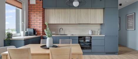 A modern kitchen with a brick accent wall, wooden cabinets, and a dining area with a table and chairs.