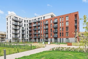 A multi-story residential building with balconies, a paved walkway, and a small park area. - Faro Beach Apartments with parking (Gdańsk)