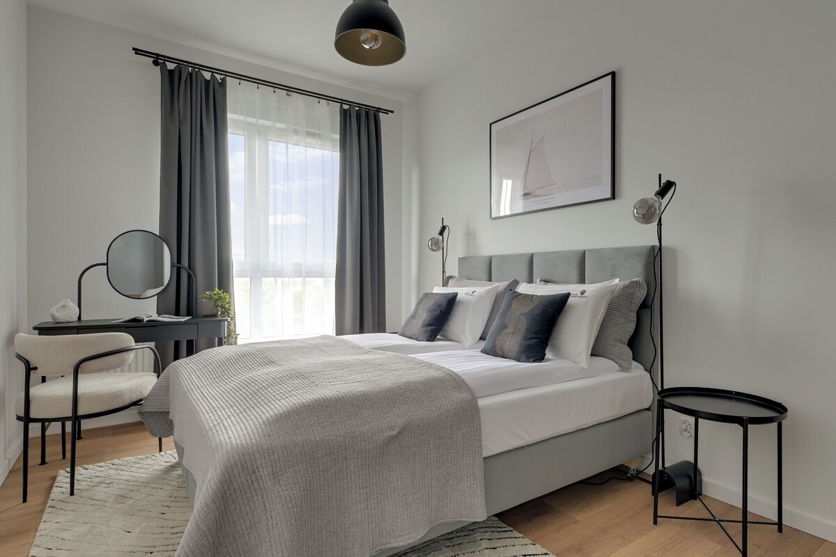 A modern bedroom with a bed, bedside tables, a desk, and a chair.