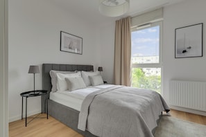 Un dormitorio moderno con una cama, una mesita de noche, una lámpara y dos cuadros en la pared.