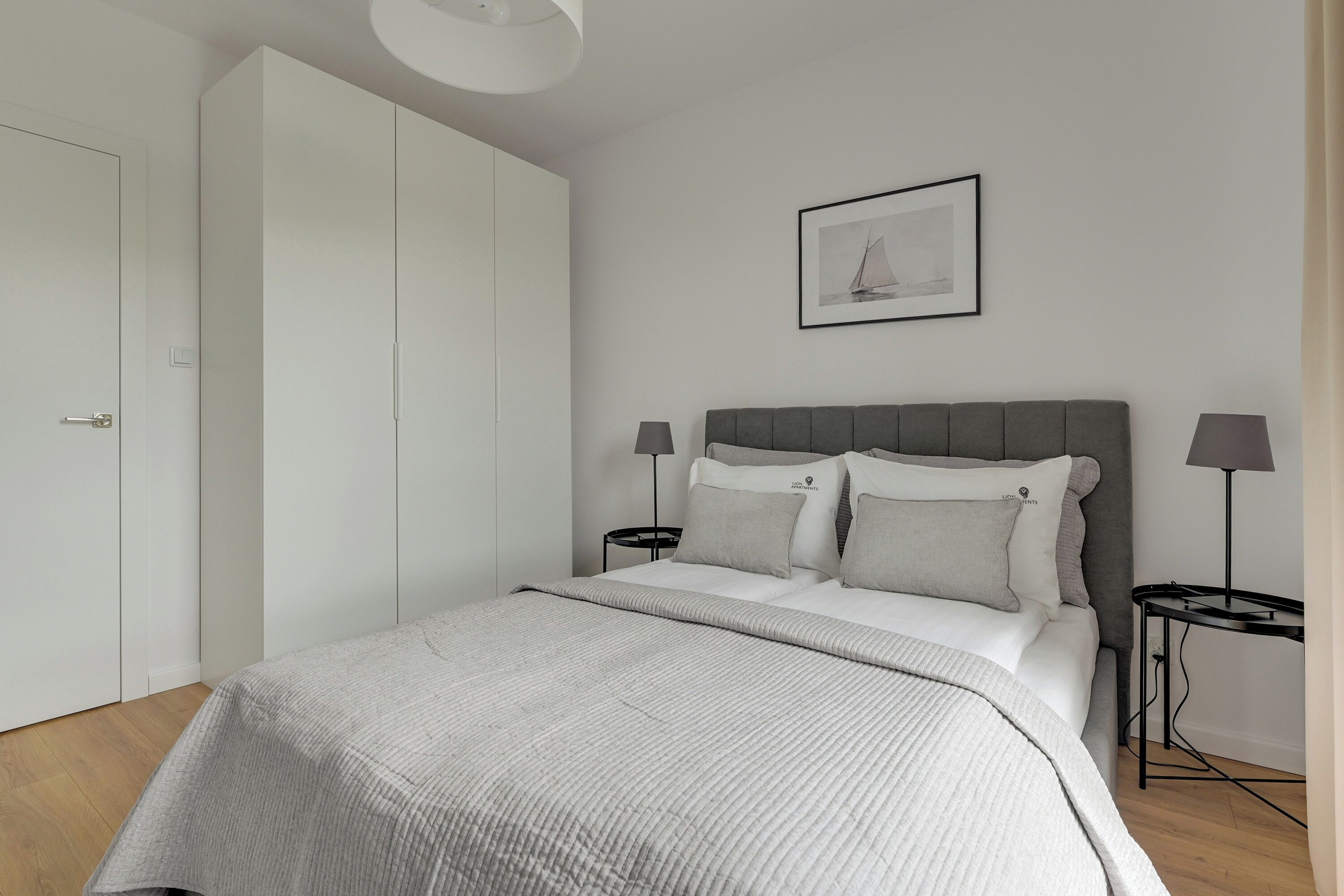 A bedroom with a bed, bedside tables, a wardrobe, and a framed picture on the wall.