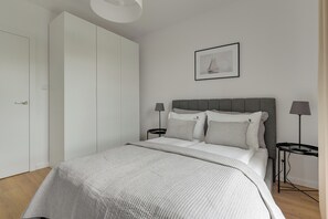 Quarto com cama, mesas de cabeceira, guarda-roupa e um quadro na parede.