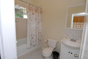 A bathroom with a toilet, sink, and shower curtain. - Charming Bed & Breakfast with amazing ocean views nestled in the hills  of Escap (Micoud)