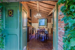 A rustic dining area with a brick wall, wooden ceiling, and a chandelier. - A Peaceful 3-Bedrooms Oasis In Orentano (Orentano)