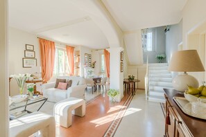 A spacious living room with a staircase, white furniture, and a dining area. - A Peaceful 3-Bedrooms Oasis In Orentano (Orentano)